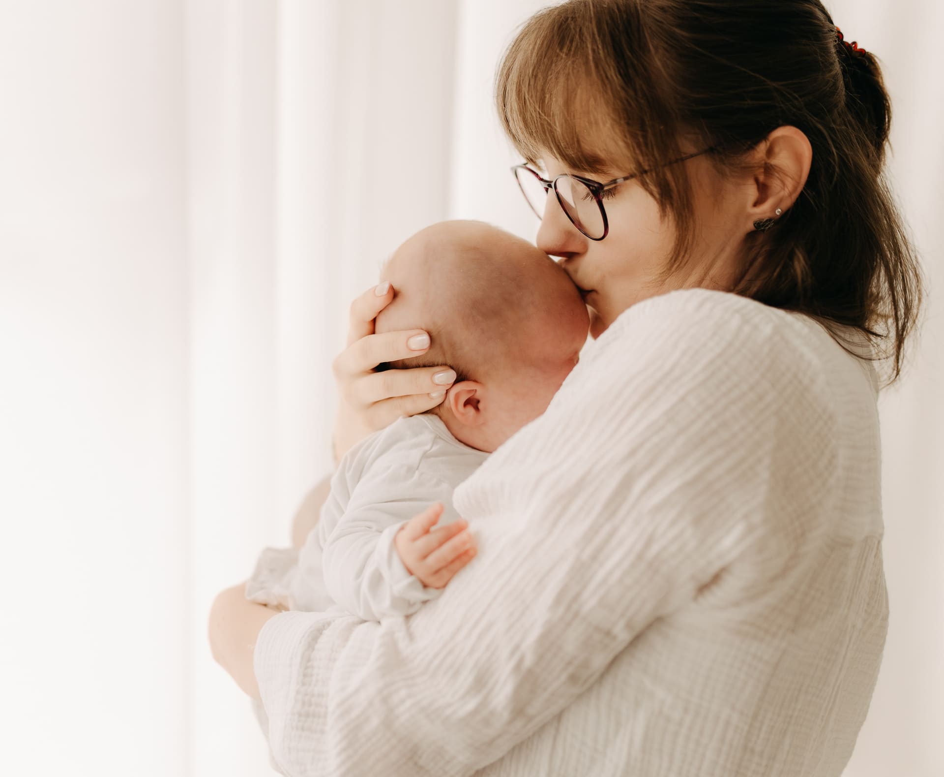 Mama küsst ihr Neugeborenes beim Newborn Shooting in Bottrop