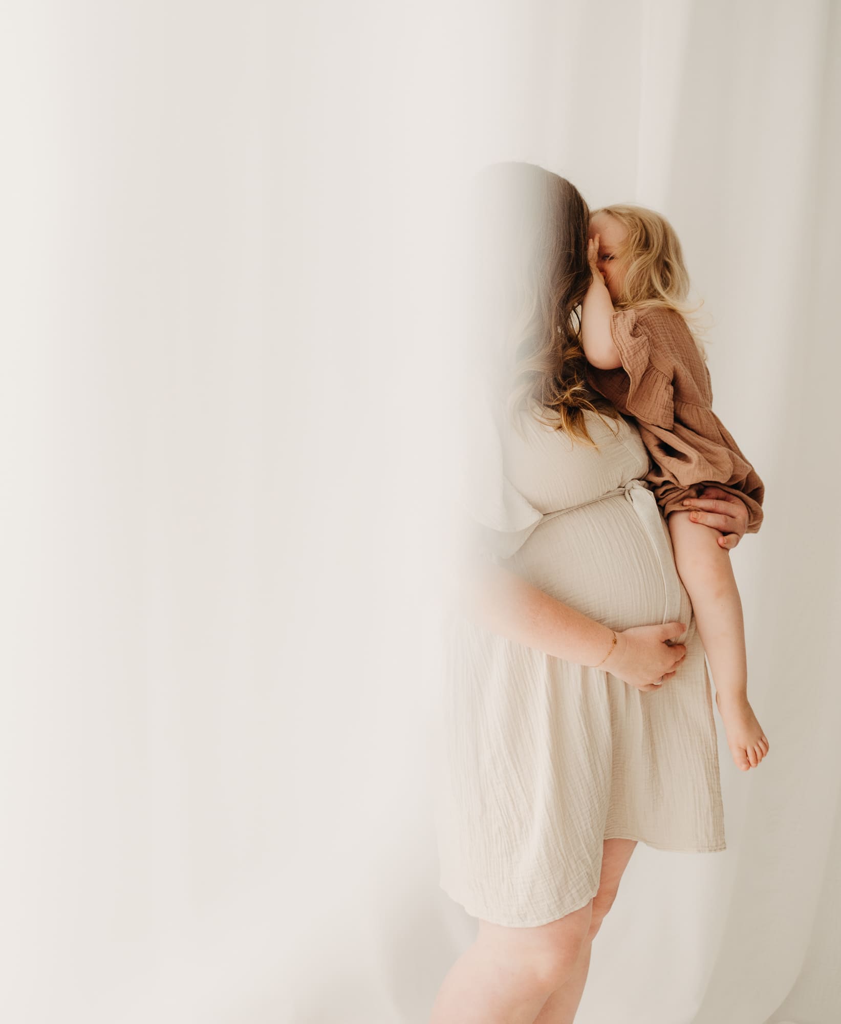 Schwangere Mutter trägt ihr Kleinkind auf dem Arm — Babybauch Shooting im Tageslichtstudio Bottrop