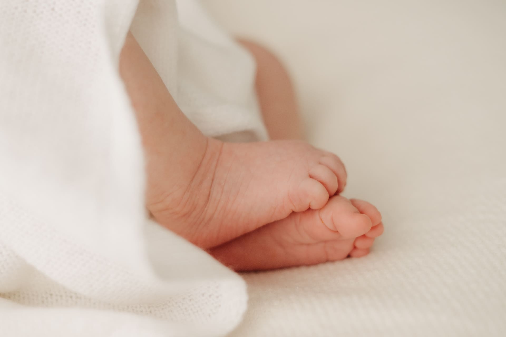 Kleine Baby-Füße auf weißem Stoff — Newborn Fotografie Bottrop